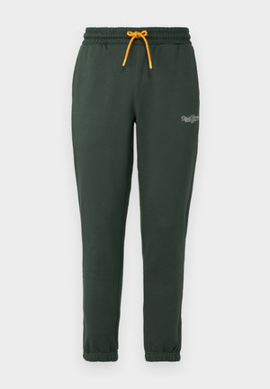 Pantalons de survêtement vert foncé en tissu doux, avec une taille élastique et un cordon jaune, ainsi que des poignets fuselés. Petit logo sur la jambe.