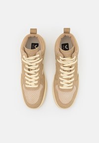 Baskets beiges avec un design en daim et cuir perforé, dotées de lacets crème, d'un col rembourré et d'une semelle intérieure de marque.