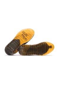 Semelle extérieure en caoutchouc avec un schéma de couleurs noir et jaune. Présente des motifs texturés et un texte gravé indiquant "MONTRÉAL."