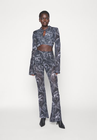 Σαλονάκι δύο κομματιών με κοντό πουκάμισο και φαρδιά παντελόνια σε μαύρη και γκρι αφηρημένη εκτύπωση, κατασκευασμένο από ένα απαλό, ελαφρύ ύφασμα.