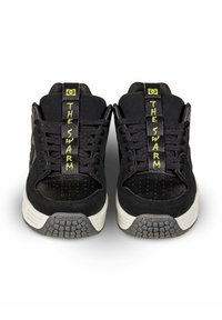 Schwarze Sneaker mit strukturiertem Wildleder und Mesh, einem gelben "THE SWARM"-Label auf der Zunge und einer Gummisohle mit Musterprofil.