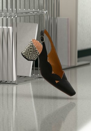 Black slingback shoe with triangular cutouts, textured fabric upper, and a patterned mid-heel in black and white geometric design.