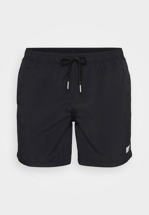 Black swim shorts with an elastic waistband and drawstring. Made from lightweight material, featuring a side logo patch and a smooth texture.