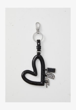 Chaveiro em forma de coração preto, feito de material brilhante com costura decorativa, ligado a um anel de metal, apresentando etiquetas de marca.