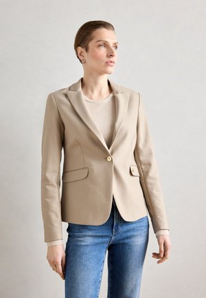 Blazer beige ajusté en tissu lisse, doté d'un unique bouton en or, de deux poches avant et d'un col structuré.