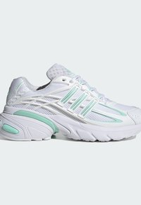 Chaussure de sport blanche avec accents vert clair, tige en mesh, semelle rembourrée et design à trois bandes sur le côté, vue du profil extérieur.