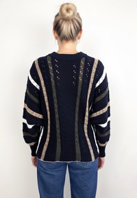 Granatowy sweter dzianinowy z ażurowymi akcentami i wielobarwnymi paskowanymi wzorami; posiada okrągły dekolt i oversize'owe rękawy.