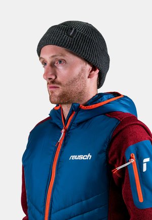 Blue insulated jacket with orange zippers, featuring a maroon textured sleeve and Reusch logo. Dark ribbed knit beanie on model's head.