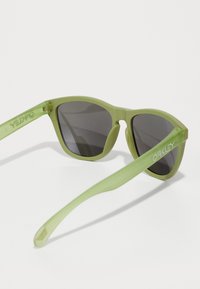Grønne gjennomsiktige solbriller med grå linser, med moderne fasong og merket "Oakley" preget på stangen. Jevn tekstur.