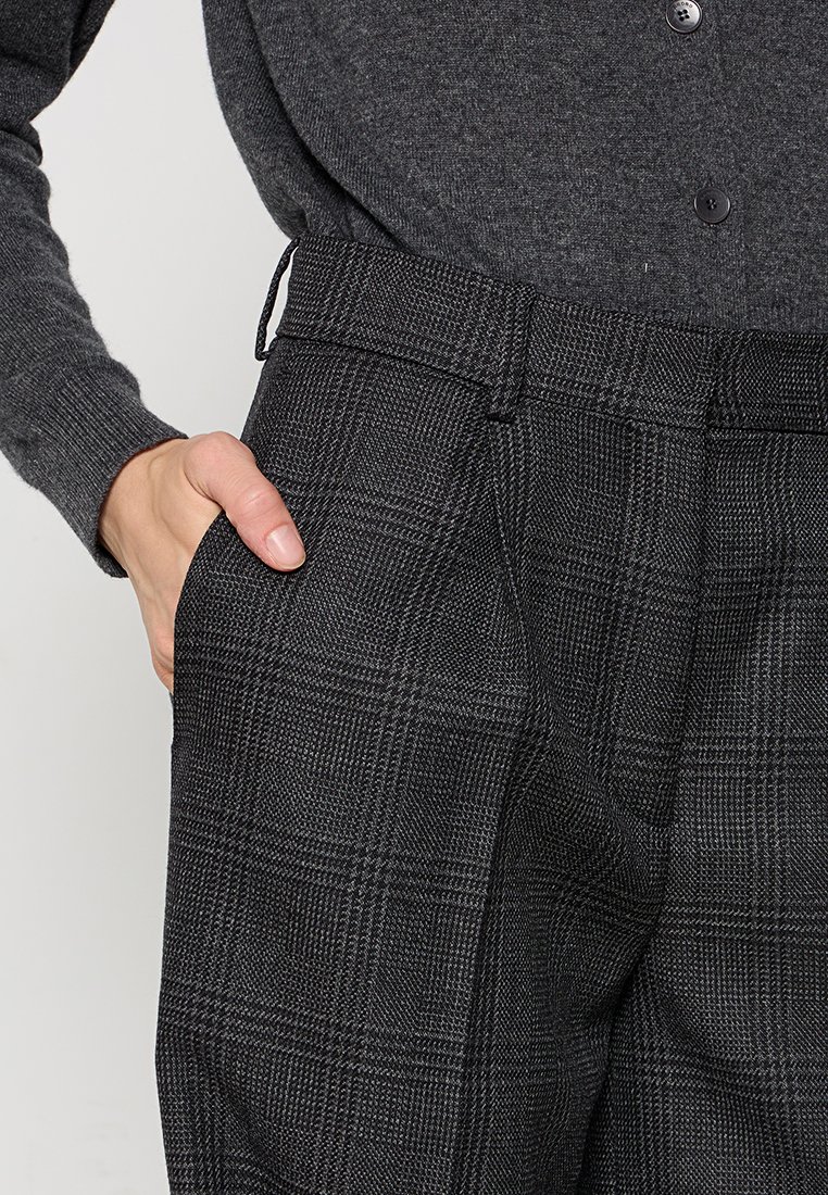 Grijze geruite broek van een gestructureerde stof, met zijzakken en een klassieke pasvorm. De tailleband heeft riemlussen voor verstelbare maatvoering.