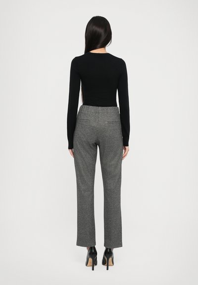 Black fitted top with long sleeves paired with grey check pattern trousers and black high-heeled shoes. Simple, tailored silhouette.