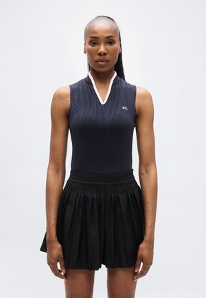 A tengerészkék ujjatlan body fehér gallérral és texturált mintázattal rendelkezik, fekete pliszírozott szoknyával, amely elasztikus derékpánttal van ellátva.