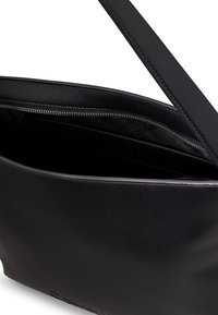Czarna skórzana torba na ramię o gładkim wykończeniu, z zapinaną na zamek kieszenią wewnętrzną i jednym długim paskiem do noszenia. Minimalistyczny design bez widocznych logo.