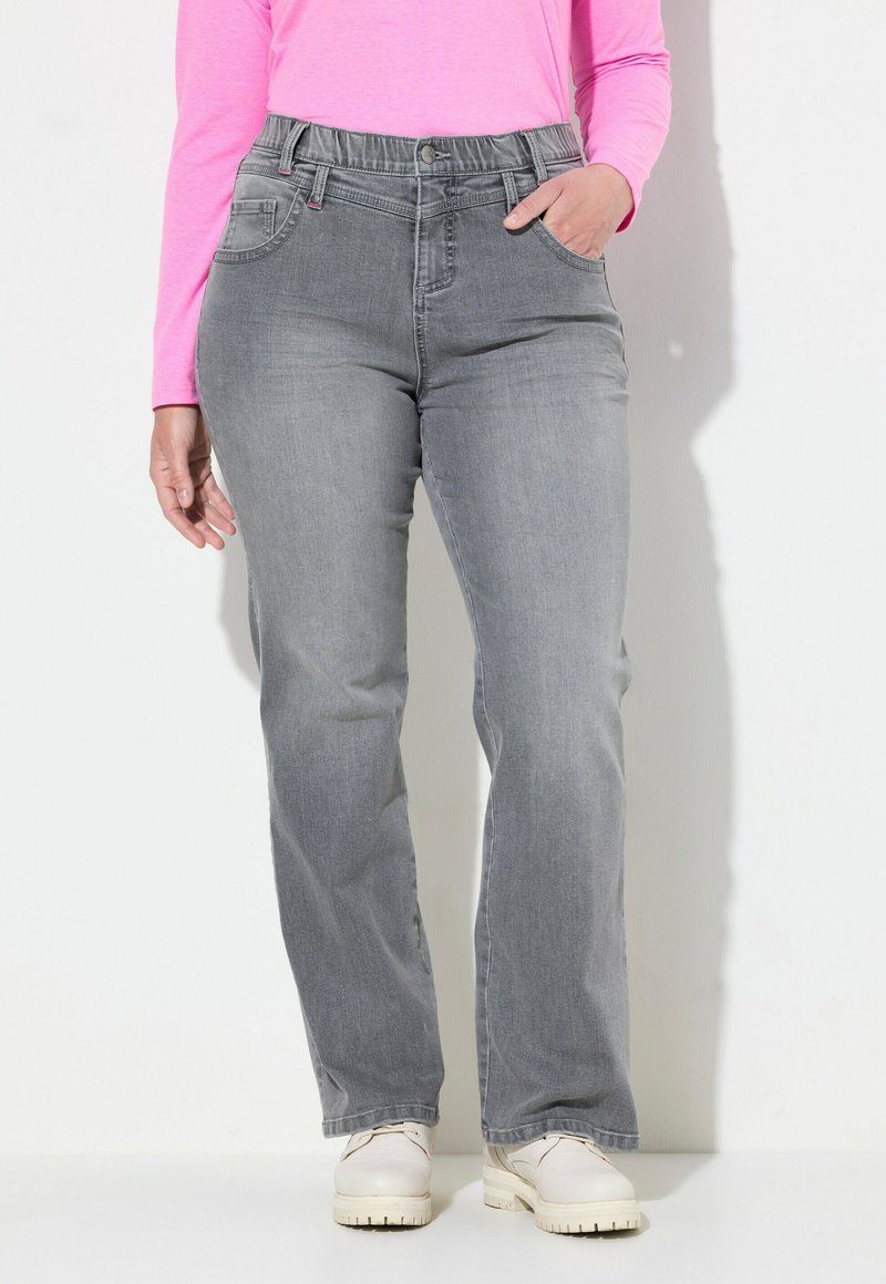 Jeans in denim grigio con vestibilità rilassata, caratterizzati da un cinturino alto, tasche frontali e una texture liscia. Abbinati a scarpe di colore chiaro.