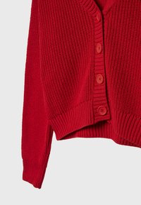 Roter Strickcardigan mit V-Ausschnitt, geripptem Muster und sechs runden Knöpfen an der Vorderseite. Der Stoff ist dick und warm.