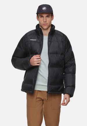 Svart puffjacka med dragkedja fram och hög krage. Har broderad logotyp på bröstet och elastiska muddarna. Lättviktig design.