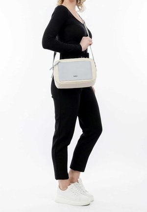 Crossbody-taske i beige og lysegrå, rektangulær form, glat tekstur, har lynlås og et logo præget på fronten.