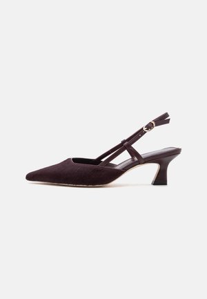 Escarpin kitten heel marron foncé à bout pointu, à bride arrière, avec bride cheville et boucle dorée sur fond clair uni.