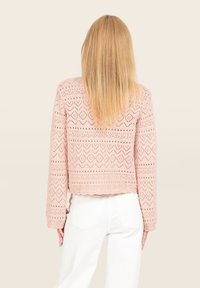 Veste tricotée rose au design court, présentant des motifs en losanges et des détails ajourés. Manches longues et ourlet festonné.