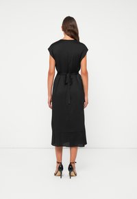 Black midi dress with short cap sleeves, tied at the back with a fabric belt. Soft, smooth texture and slightly sheer hem detail.