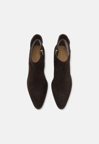 Tmavě hnědé semišové kotníkové boty s špičatou špičkou, bočním zipem a hladkým vnitřním podšíváním. Vyznačují se minimalistickým designem a elegantní siluetou.