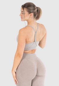 Sujeción deportiva gris claro y leggings de cintura alta a juego, hechos de un suave tejido texturizado con diseño sin costuras y correas ajustables.