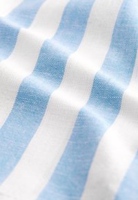 Tissu en coton présentant des rayures alternées bleues et blanches, avec un tissage texturé, créant un aspect doux et légèrement froissé.