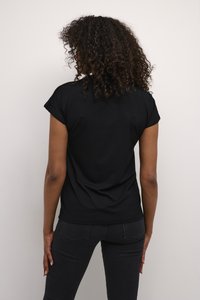 Chemise noire à manches courtes avec une coupe décontractée, texture lisse et détails de couture subtils, associée à un jean ajusté noir.