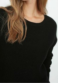 Schwarzer Strickpullover mit einem gerippten Muster, rundem Halsausschnitt und langen Ärmeln. Der Stoff wirkt weich und warm, geeignet für kühleres Wetter.