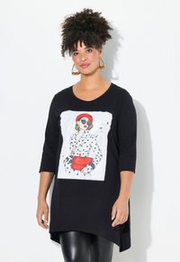 Schwarze Tunika mit kurzen Raglansärmeln, die eine gedruckte Illustration einer Frau in gepunktetem Outfit, rotem Barett und roter Handtasche zeigt.
