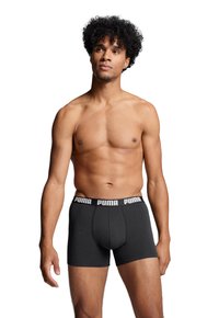 Black boxer shorts made of a soft fabric with an elastic waistband featuring white "PUMA" branding. The design is fitted and seamless.