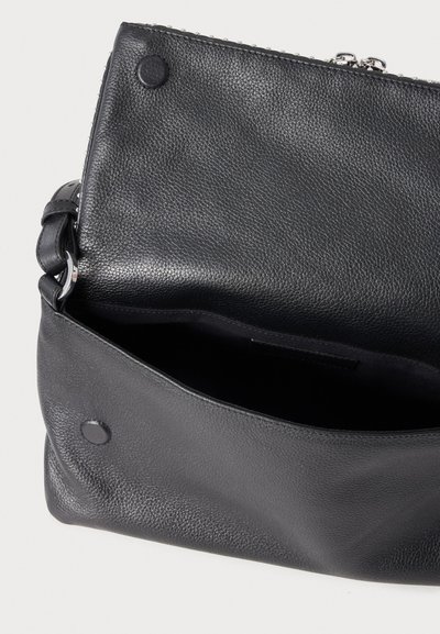 Μαύρο δερμάτινο τσαντάκι ώμου με ανάγλυφη πτερυγική επένδυση ανοιχτή, αποκαλύπτοντας άδειο εσωτερικό και μαγνητικά κλικ κλείστρα εμπρός και στην πτέρυγα.