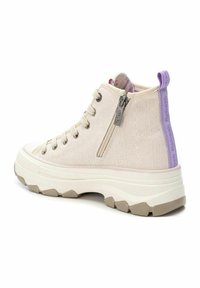Zapatillas altas beige con tejido texturizado, suela blanca y gris claro, que cuentan con un zipper lateral y un acento lila en la parte trasera.