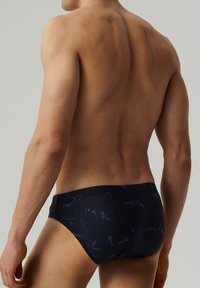 Granatowe kąpielówki w formie majtek z subtelnym, abstrakcyjnym wzorem w ciemnoniebieskim kolorze. Wykonane z gładkiego materiału, z dopasowanym krojem i elastycznym pasem.