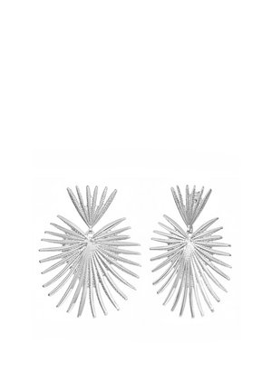 Boucles d'oreilles en métal argenté en forme de feuilles de palmier superposées et texturées avec plusieurs pointes fines et allongées.