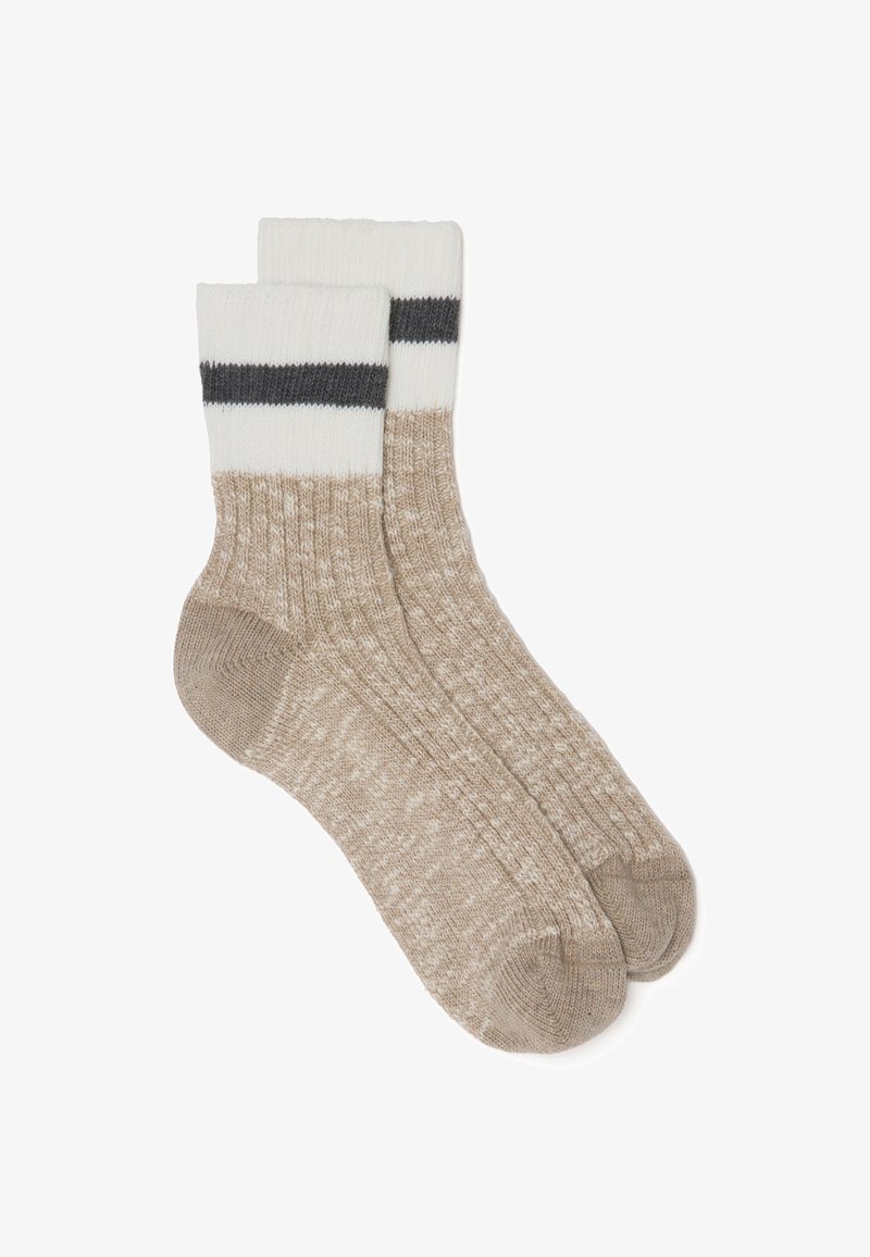 Calze lavorate a maglia beige con un motivo testurizzato. La parte superiore presenta un risvolto bianco con una striscia grigio scuro. Morbide, confortevoli e di lunghezza media, fino al polpaccio.