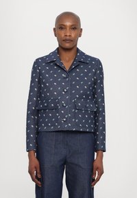 Marineblauwe cropped jas met bloemenborduursel, twee voorzakken en knoopsluitingen. Textuurstof en klassiek kraagontwerp.