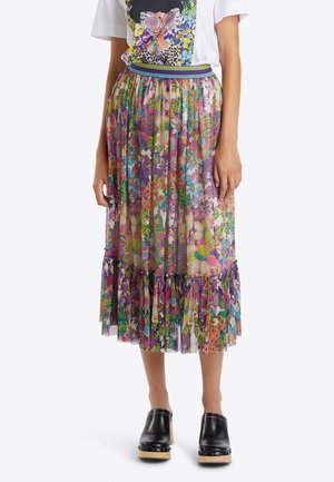 Falda maxi floral transparente con flores multicolores, bajo con volantes y cintura elástica; combinada con una camiseta gráfica y zuecos negros.