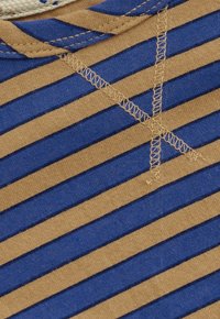 Close-up van bruin en blauw gestreepte stof met beige draadsteken die een X-vorm vormen nabij een touwdetail.