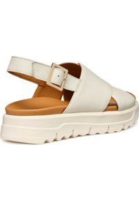 Sandalia blanca de cuero con un diseño de tiras cruzadas, hebilla ajustable en el tobillo y una suela gruesa texturizada en crema que contrasta con una plantilla color marrón.
