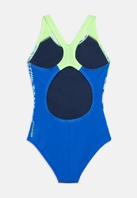 Μαγιό με κυρίως μπλε σώμα, ανοιχτό πράσινες λεπτομέρειες και σχεδιασμό ανοιχτής πλάτης. Διαθέτει ραφές και λογότυπο στην αριστερή πλευρά.