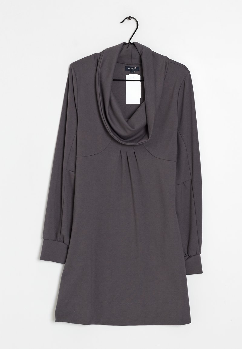 Robe grise à manches longues avec un col drapé, des détails plissés à l'avant et des poignets ajustés. Fabriquée dans un tissu doux, elle comporte une étiquette fixée près du col.