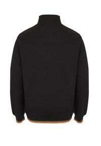 Zwarte jas met een hoge kraag, elastische manchetten en een geribde tailleband met een contrasterende tan-streep aan de onderkant.