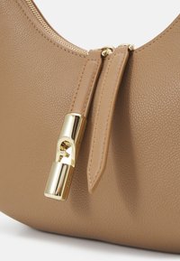 Borsa in pelle tan con finitura testurizzata, dotata di cerniera dorata e dettagli in hardware. Il design è minimale e presenta una forma curvata.