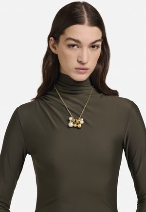 Colier cu lanț auriu, cu mărgele mixte, inclusiv perle albe și accente aurii, purtat peste un top strâmt de culoare verde măsliniu, cu decolteu înalt.