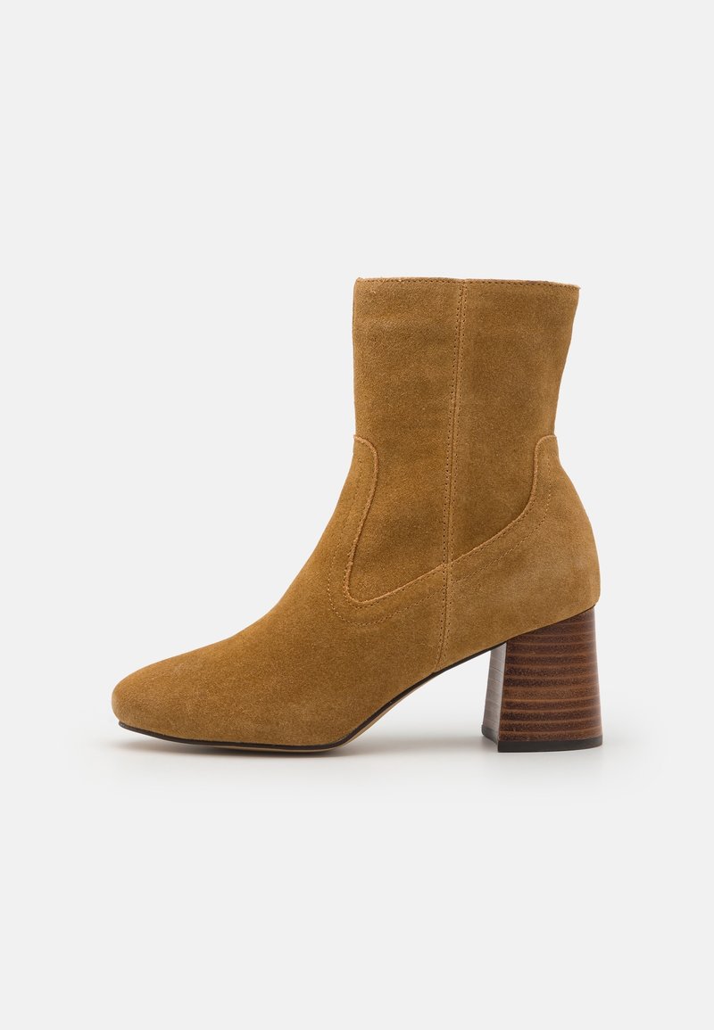 Botte mi-hauteur en daim camel avec bout arrondi et talon épais empilé, présentant des détails de couture subtils le long des côtés.