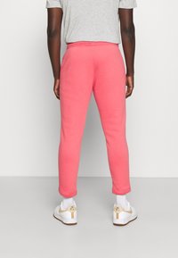 Rosa sweatpants med smal passform, elastisk midjeband och ribbad mudd, kombinerat med vita sneakers och ankelsockor.