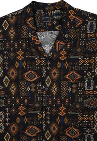 Chemise noire à manches courtes avec un motif géométrique agrémenté d'accents orange, bleu et blanc. Le tissu est doux, avec une coupe décontractée et une fermeture à bouton.