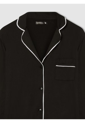 Maglia da pigiama nera con bottoni, con piping bianco lungo il colletto, il pattino e il bordo della tasca sul petto, tasca sul petto a sinistra.