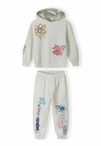 Haut à capuche gris clair avec une poche avant, imprimés floraux et graffiti dans des tons de violet, bleu et rose. Pantalon de jogging assorti avec des motifs similaires.